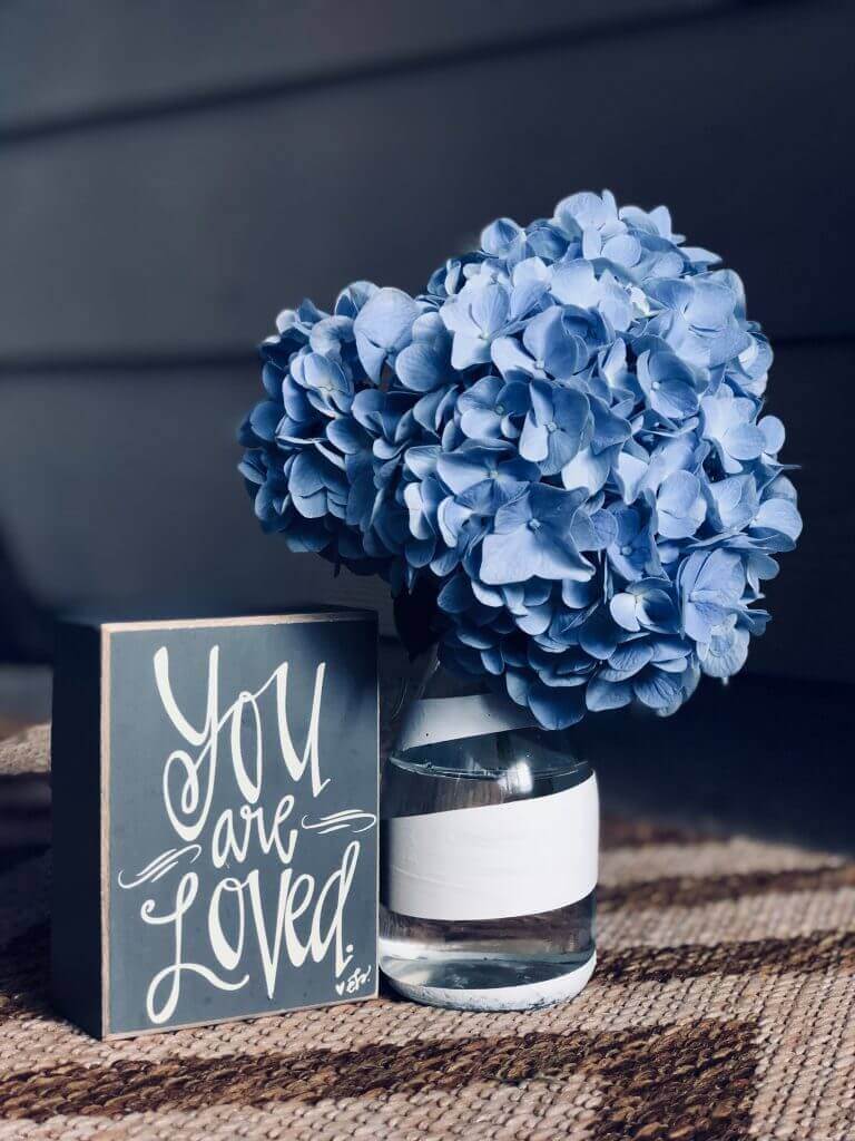 Blue flowers beside "You are Loved" Sign